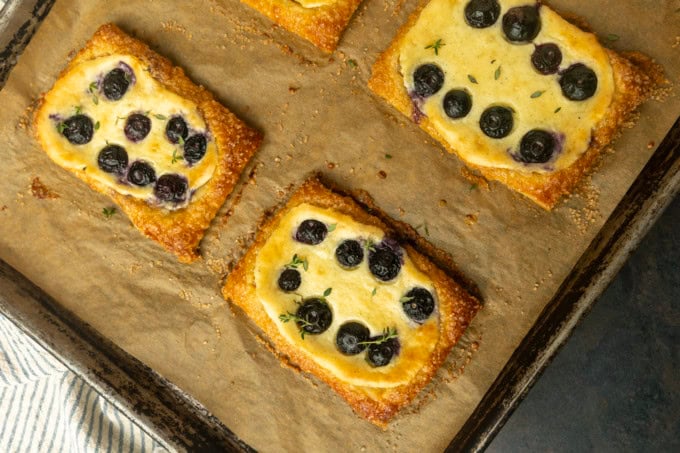 blueberry cream cheese puff pastry with thyme on parchment lined pan