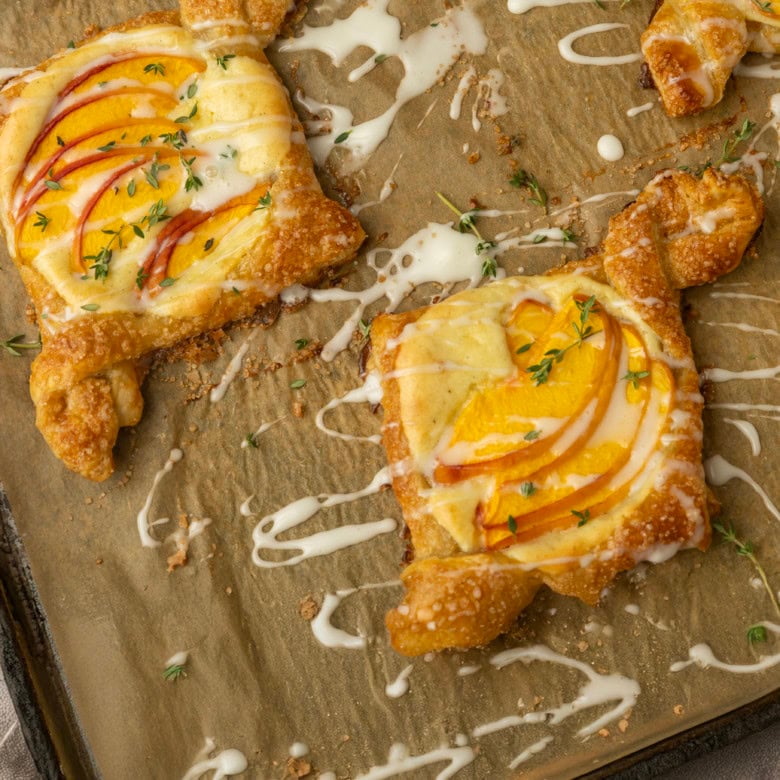 peach cream cheese puff pastry with thyme on parchment lined pan
