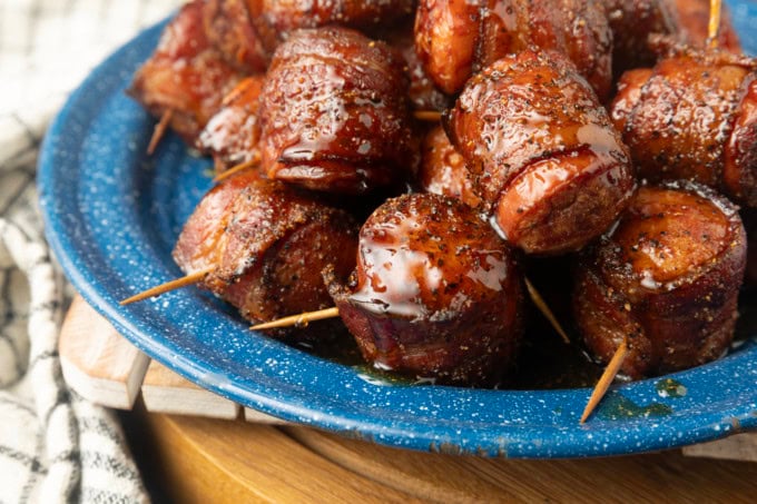 air fryer kielbasa bites wrapped with bacon drizzled with honey on a blue plate