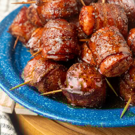 air fryer kielbasa bites wrapped with bacon drizzled with honey on a blue plate