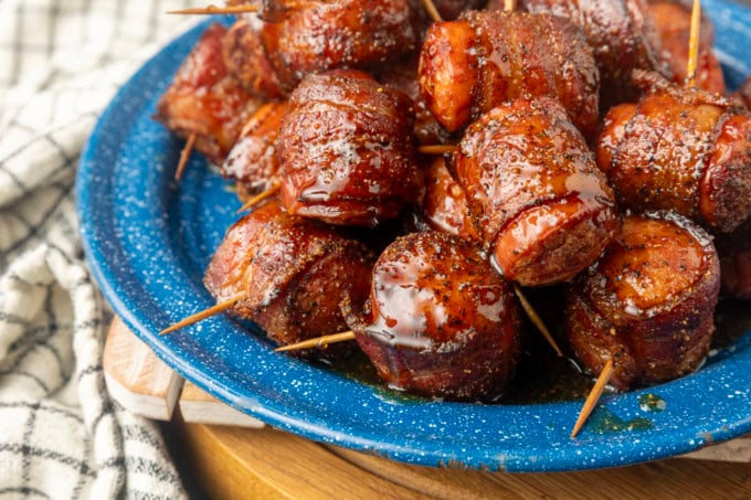 air fryer kielbasa bites wrapped with bacon drizzled with honey on a blue plate