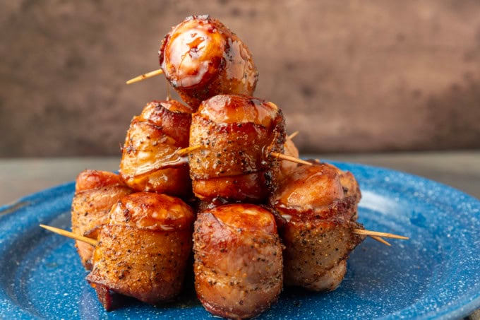 air fryer kielbasa bites wrapped with bacon drizzled with honey on a blue plate