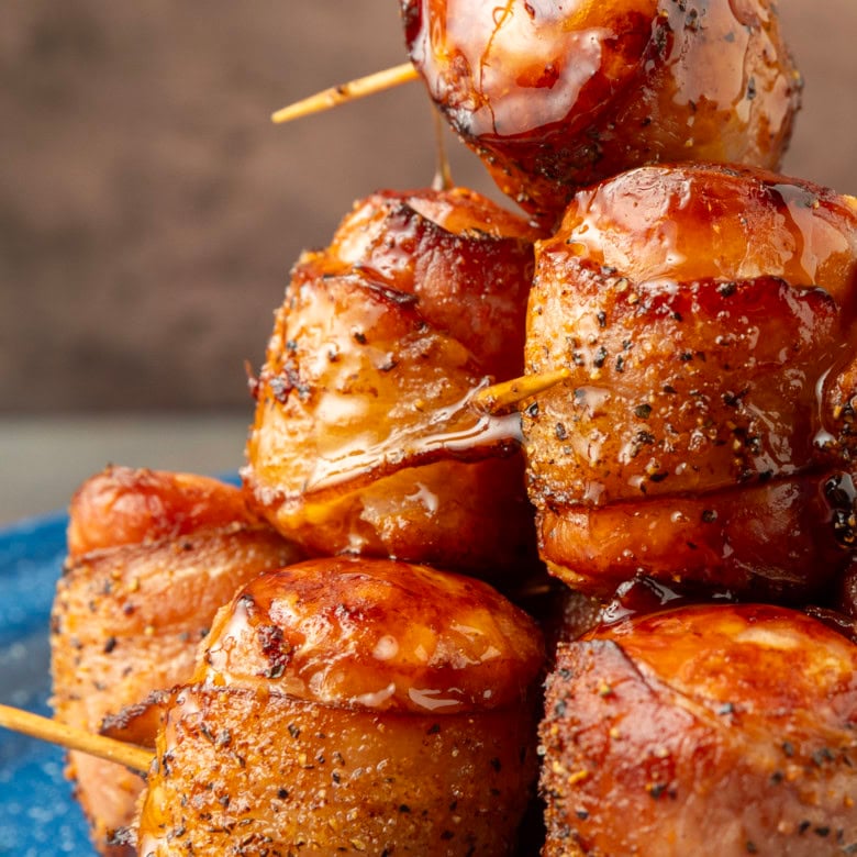 air fryer kielbasa bites wrapped with bacon drizzled with honey on a blue plate