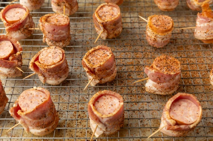 seasoned kielbasa in air fryer bites wrapped with bacon on a cooling rack