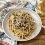 miso mushroom pasta with a fork on a plate with a glass of white wine