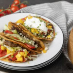 smash tacos on stacked plates with toppings in bowls