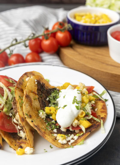 smash tacos on stacked plates with toppings in bowls