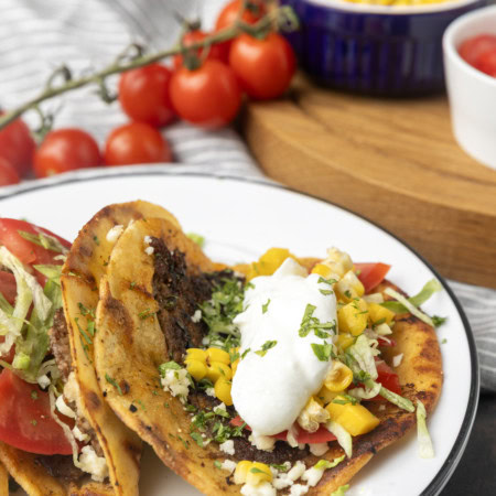 smash tacos on stacked plates with toppings in bowls