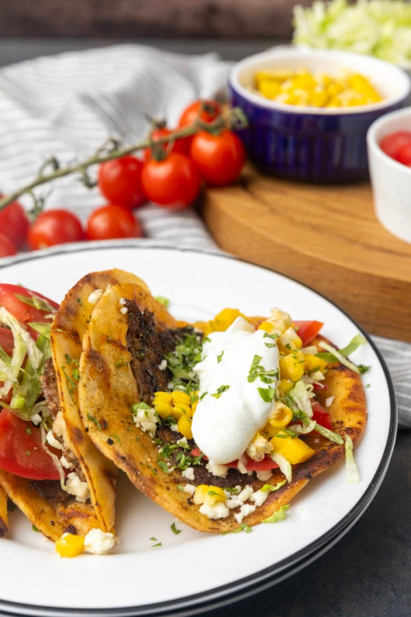 smash tacos on stacked plates with toppings in bowls