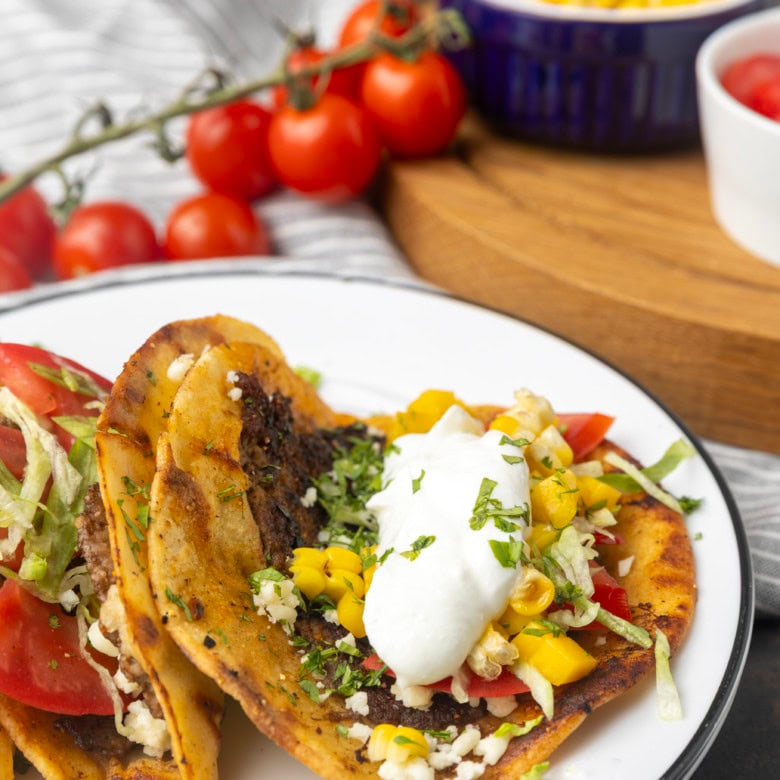 smash tacos on stacked plates with toppings in bowls