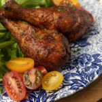 smoked chicken drumsticks on a blue and white plate with cherry tomatoes