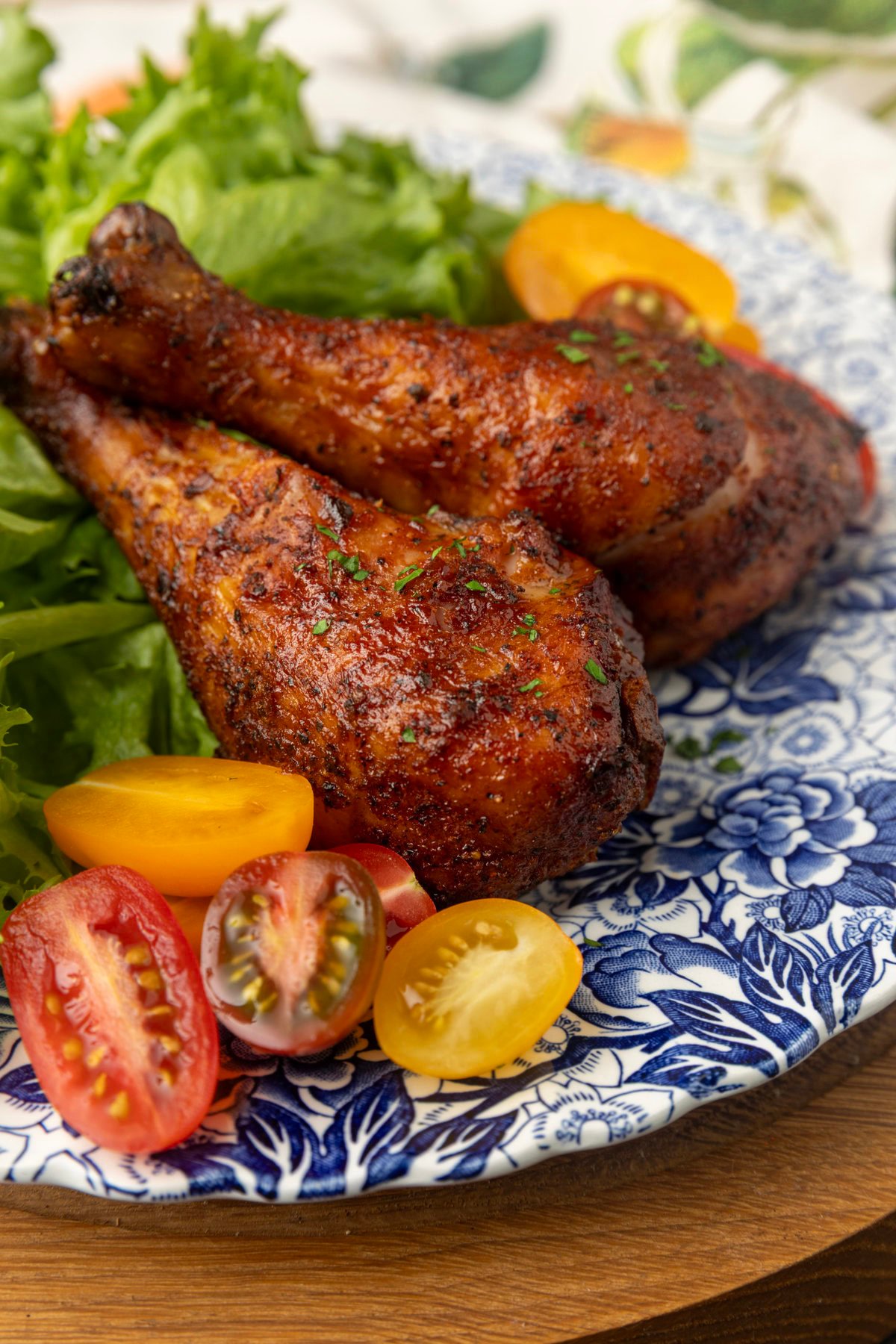 smoked chicken drumsticks on a blue and white plate with cherry tomatoes