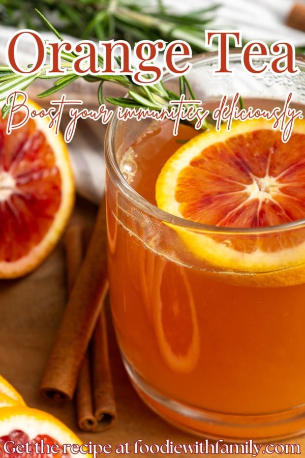 Orange tea in a mug with a slice of orange, a cinnamon stick, and a sprig of rosemary.