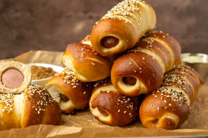 pretzel dogs on parchment paper on a pan with a variety of dipsa