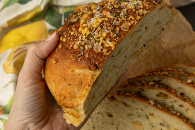 partially sliced one hour rosemary parmesan bread held in a hand