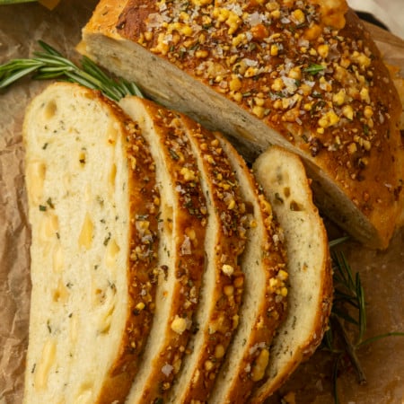 partially sliced one hour rosemary parmesan bread on parchment paper