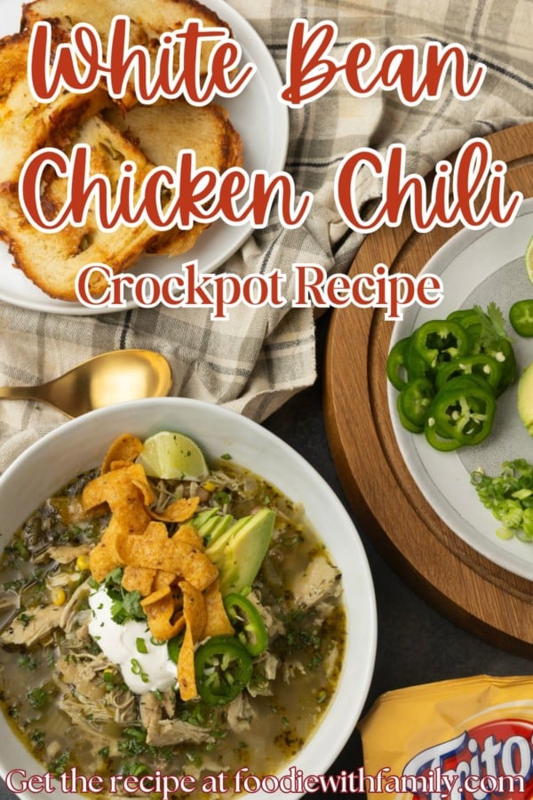 white bean chicken chili in a bowl with avocados, jalapenos, sour cream, cilantro, fritos, and lime wedges with text overlay describing the photo