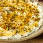 whipped goat cheese appetizer in a pottery bowl with crostini, salami, and grapes