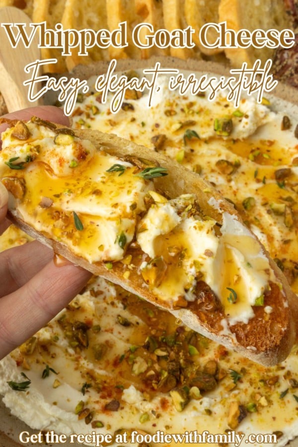 whipped goat cheese appetizer in a pottery bowl with crostini, salami, and grapes and text overlay describing the photo