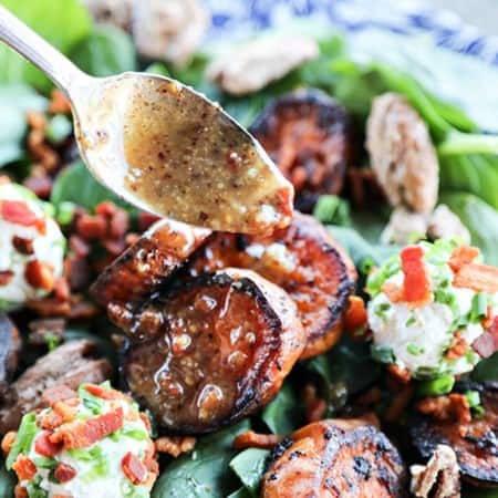 Hot Bacon Vinaigrette Dressing drizzled from antique metal spoon over melting sweet potatoes, baby spinach, crumbled bacon, chopped chives, maple candied pecans