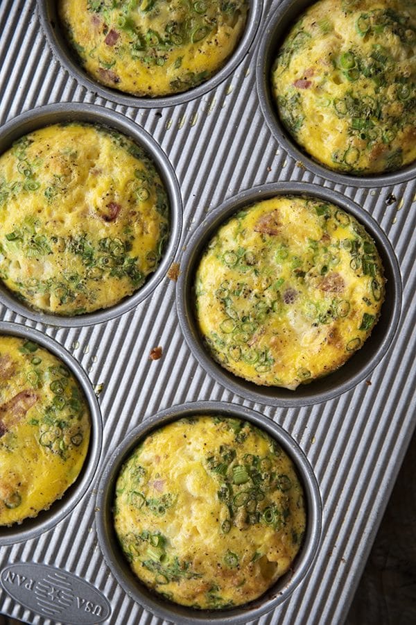 Muffin Tin Eggs; craveable crisped ham, green onions, Cheddar cheese, and egg baked to puffy, golden perfection. These egg muffins are a perfect topper for toasted English muffins or beside a salad for a full, light meal.