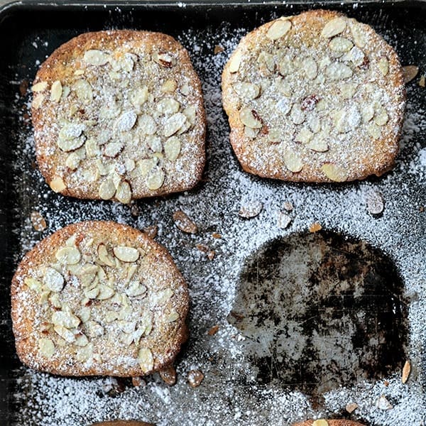 Nutella Raspberry Bostock, brioche with frangipane, Nutella, and raspberry jam, dusted with powdered sugar and almonds on distressed sheet pan