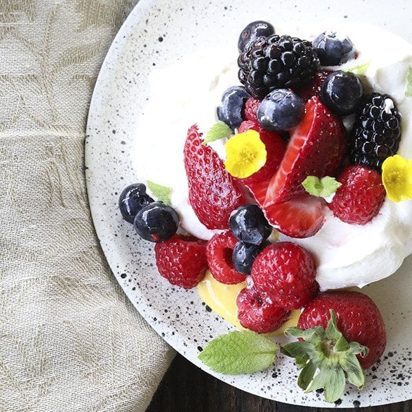 Ethereally light, crisp on the outside, marshmallowy on the inside, this Mini Pavlova Recipe is topped with lemon curd, berries, whipped cream, and ready for summer!
