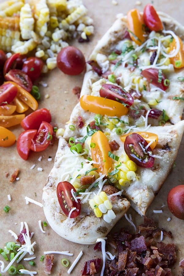 freshly grilled flatbread with bacon, corn, tomatoes, and cheese