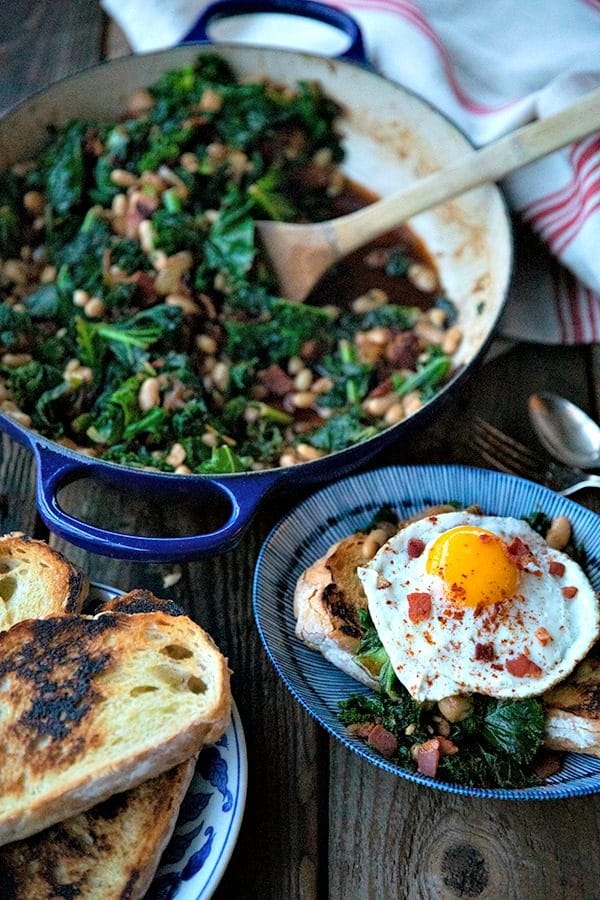 Tender beans and greens, caramelized onions, savoury bacon, sliced garlic, smoked paprika, and a hint of spice, star in this one-pot, low cost, crowd-pleaser served over indulgently thick slices of crunchy-edged, pan toasted garlic bread.