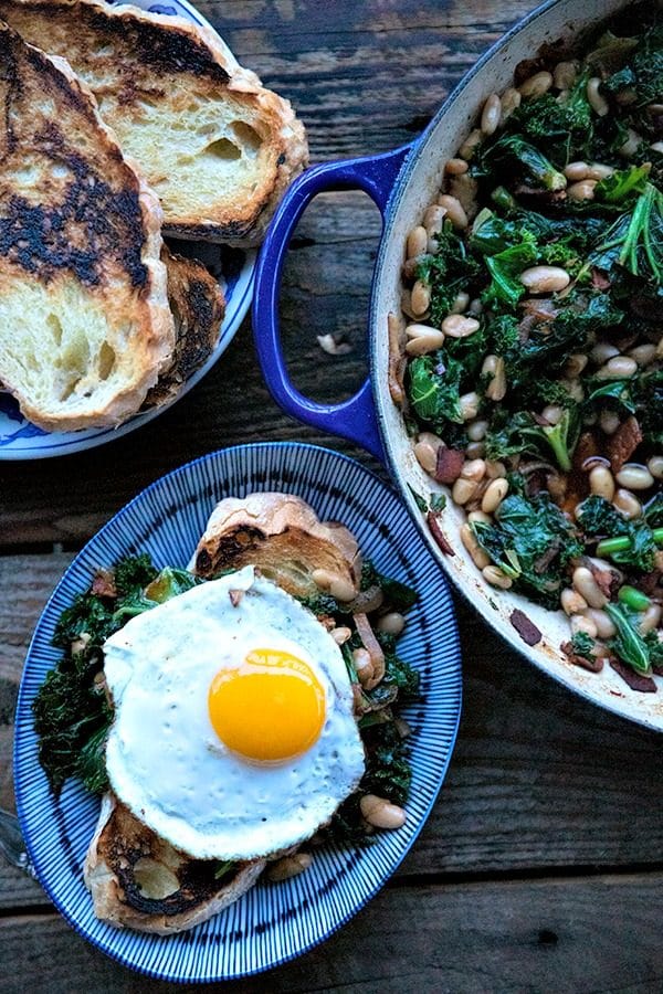 Tender beans and greens, caramelized onions, savoury bacon, sliced garlic, smoked paprika, and a hint of spice, star in this one-pot, low cost, crowd-pleaser served over indulgently thick slices of crunchy-edged, pan toasted garlic bread.