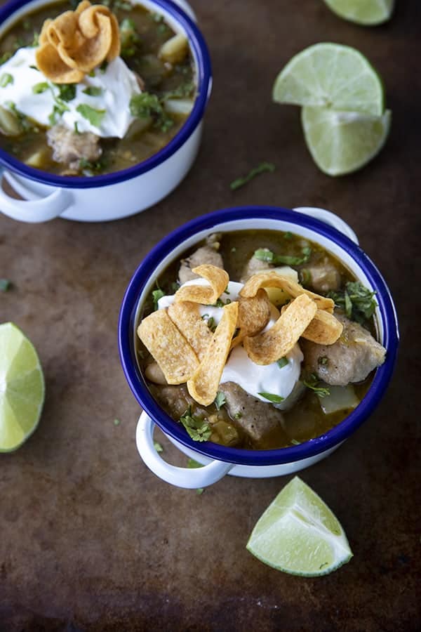 PORK GREEN CHILI IN A WHITE ENAMEL BOWL WITH A BLUE RIM AND HANDLES