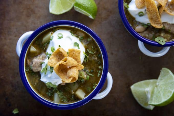 PORK GREEN CHILI IN A WHITE ENAMEL BOWL WITH A BLUE RIM AND HANDLES